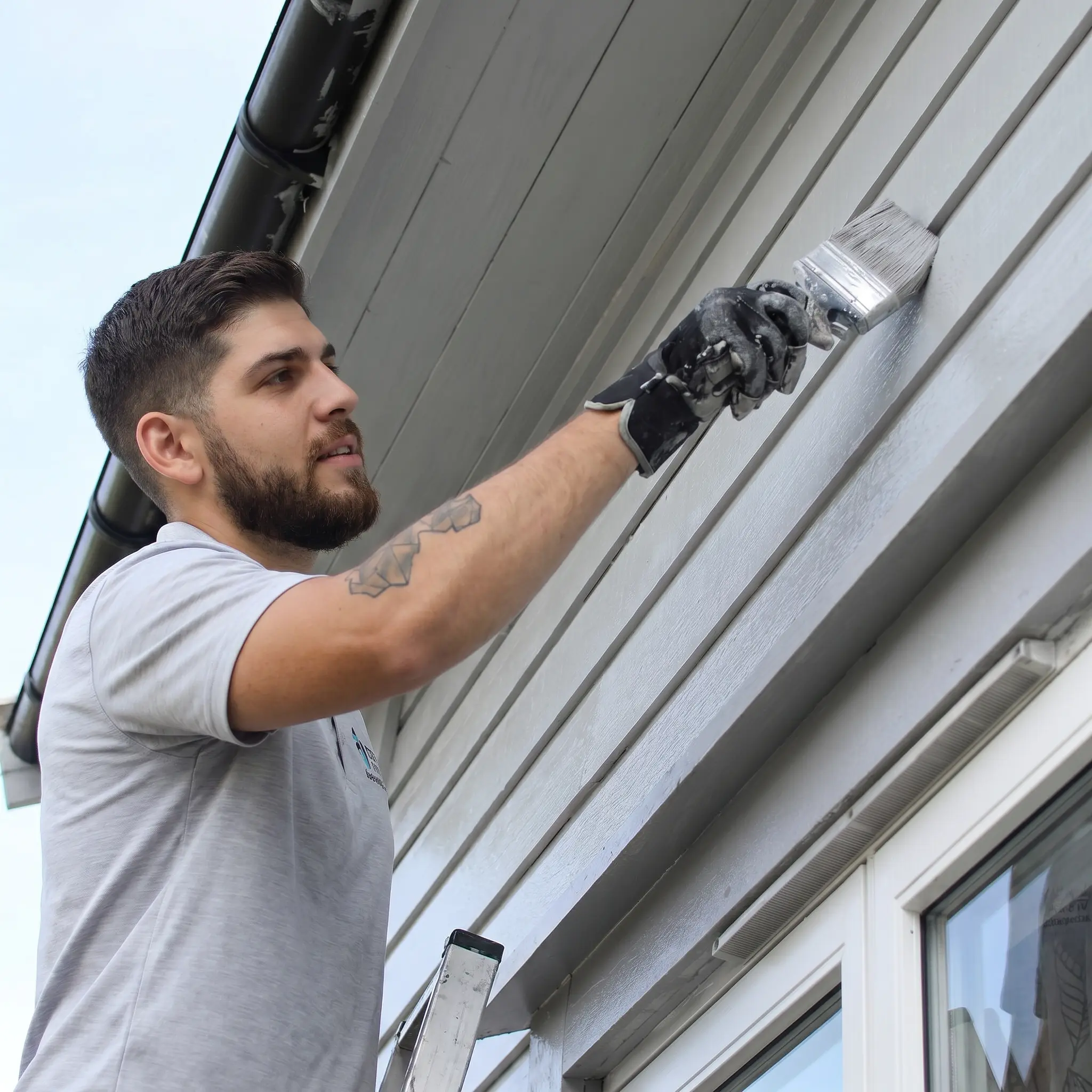 Residential exterior painting contractor applying a fresh coat of paint to home siding with precision brushwork and premium finish.